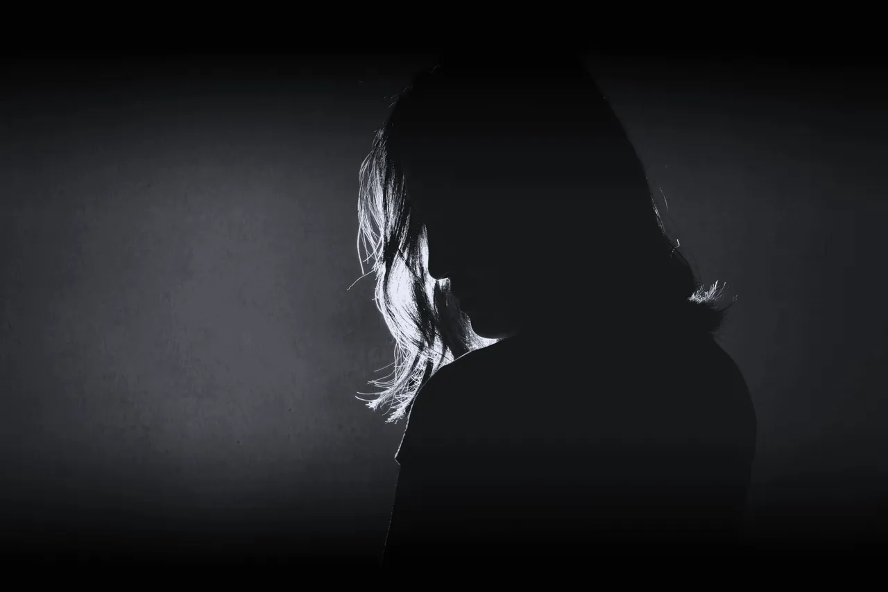 Black-and-white portrait of a woman in profile, half her face in shadow.